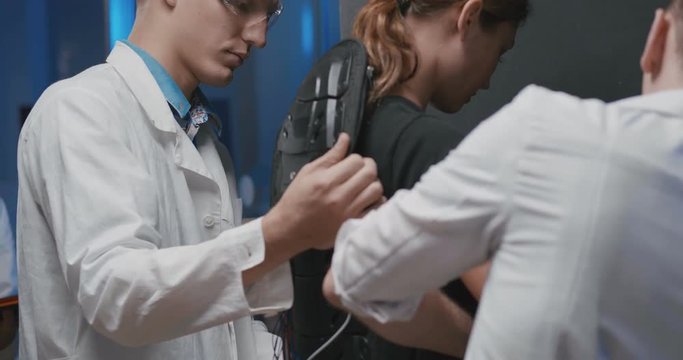 Engineers putting robot control suit on woman
