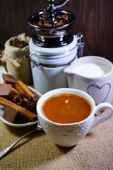 Aromatic hot coffee with milk in a cup and in beans, spices and chocolate
