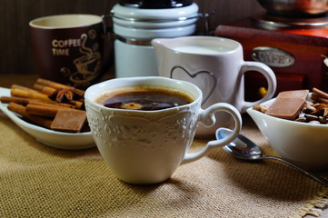 Aromatic hot coffee in a cup and in beans, spices and chocolate
