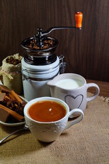 Aromatic hot coffee with milk in a cup and in beans, spices and chocolate
