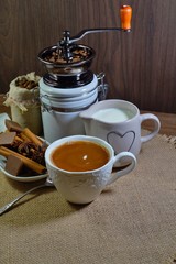 Aromatic hot coffee with milk in a cup and in beans, spices and chocolate
