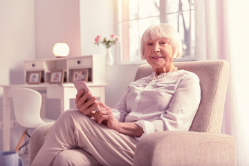 Positive grey-haired mature lady checking her phone
