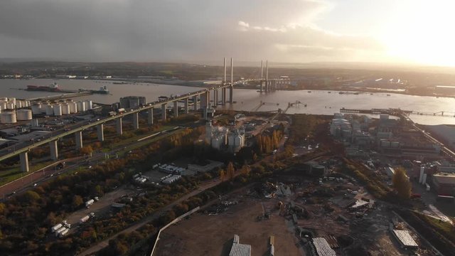 Flying over an industrial estate near Dartford Crossing tunnel and Queen Elisabeth II bridge at sunset