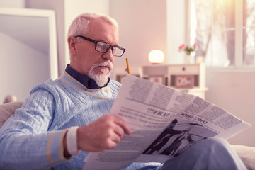 Pensive concentrated elder man reading fresh news