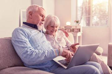 Curious pair of pensioners working with laptop