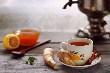 Obraz na płótnie Canvas A cup of ginger tea, ginger roots, vintage samovar, lemon and honey