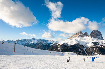 Fototapeta na wymiar Skiers skiing down the slope in Val Di Fassa ski resort in Dolomites, Italy