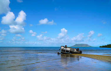 Fototapeta na wymiar Landcruiser wreck overturned on the beach at low tide