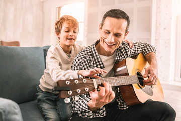 Fototapeta premium Smart little kid giving his dad a piece of musical advice.