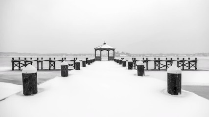 Looking out over a snow covered pier at a large frozen river, calm and still. - Powered by Adobe