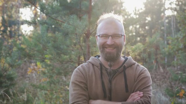 The average pocket plan of a charismatic adult man in a good mood. Object in rectangular glasses with black frame and beard pigtail Garibaldi smiles, arms folded on his chest and looking at the camera