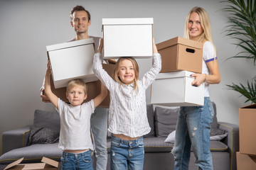 Full-length photo of happy married couple with children with cardboard boxes in their hands standing