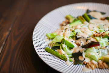 Close up Healthy salad with avocado , walnuts and grilled asparagus . Vegan food on dark wooden table.