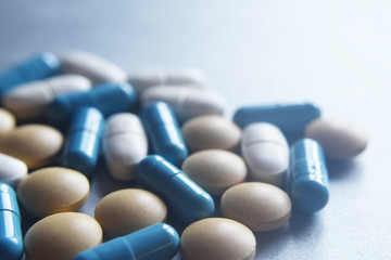 Different color blurry medical pills and capsules on grey background with copy space for text at shallow depth of field. Pharmacy, healthcare and addiction concept.