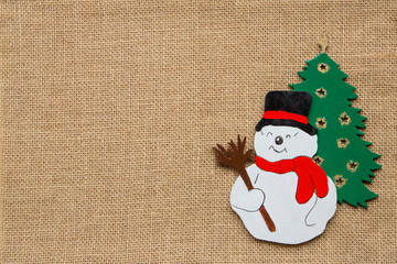 Schneemann und Christbaum auf Hintergrund aus Jute mit grossem Textfeld