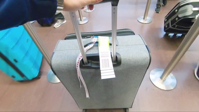 A passenger pushing the luggage on wheels in slow motion at the baggage drop in the airport.