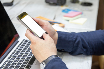 Close up of male hands using mobile phone blank white color copy space for your text message with laptop in cafe on white desk