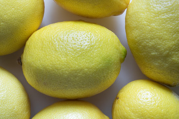 bunch of ripe yellow lemons lie on white paper