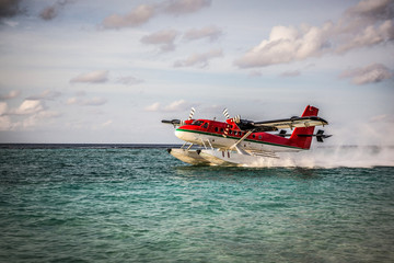 Seaplane landing in the ocean lagoon. The takeoff of a seaplane from the ocean beach.