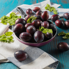 Flat lay view of ripe plums, on old wooden white background.
