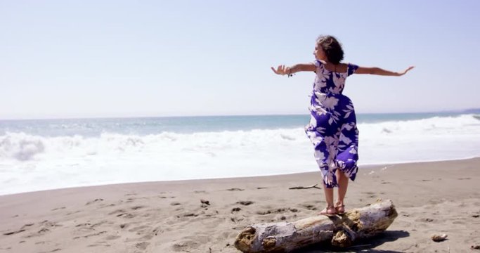 Beautiful young woman lowers arms after deep joyous beath by the ocean