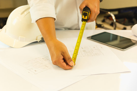 Architecture hand measuring blueprint with tape masure on working table.