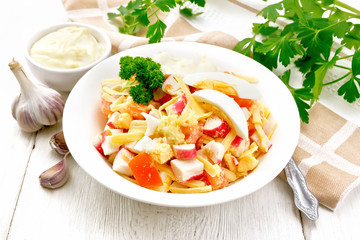 Salad of surimi and tomatoes with eggs on wooden board