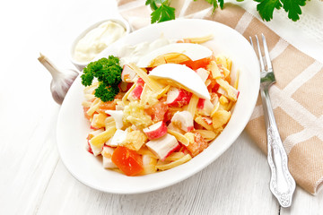 Salad of surimi and tomatoes with eggs on wooden table