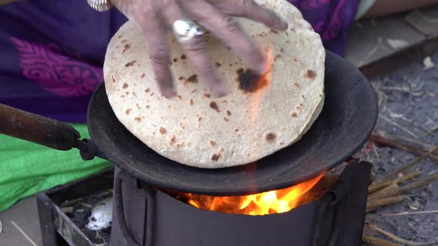 Indian woman cooking traditional indian bread, chapati cooking on open fire in Udaipur, Rajasthan, India. Close up