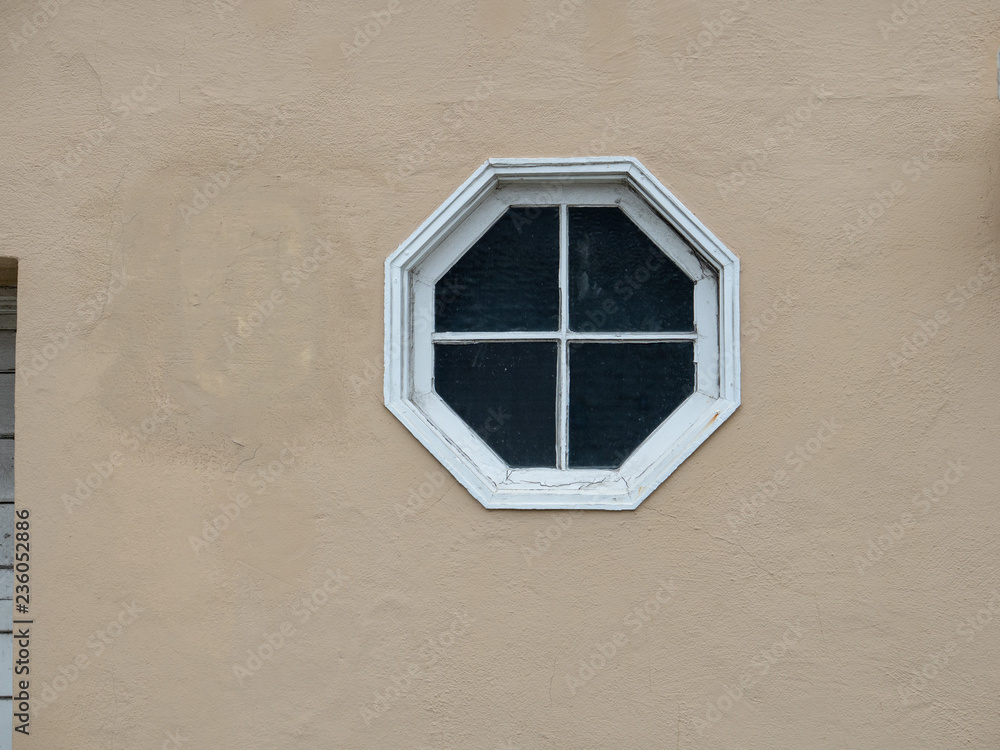 Wall mural octagon shaped glass window on the side of beige house