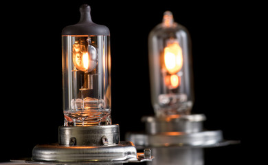 Incandescent lamp for dipped and main beam headlights with burning spiral on a black background