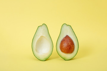Two slices of avocado isolated on yellow background