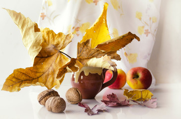 Autumn still life with yellow maple leaves, apples and nuts.
