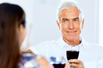 Senior man with holding a glass of wine indoors