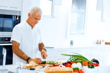Portrait of a smart senior man standing in kitchen