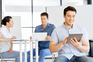 Young handsome businessman using his touchpad sitting in office