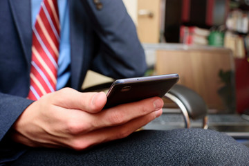 Young businessman with smartphone in his hand in office, close-up picture