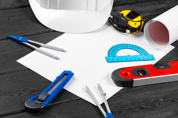 Close up white hardhat and variety of repair tools with copy space in the middle over wooden background