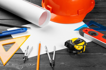 Close up orange hardhat and variety of repair tools with copy space in the middle over wooden  background