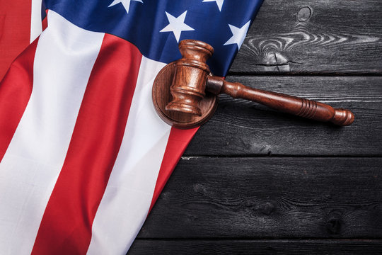 Wooden gavel and USA flag on table close up