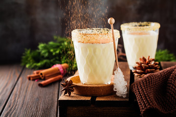 Eggnog Traditional Christmas drink milkshake with cinnamon on dark old background. Selective focus.