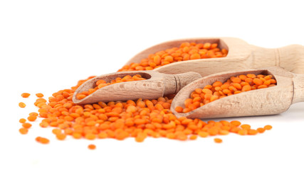 Red lentils in the wooden spoon, isolated on white background