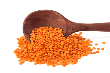 Red lentils in the wooden spoon, isolated on white background