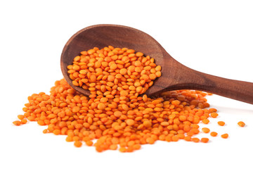 Red lentils in the wooden spoon, isolated on white background