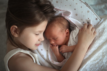 Sleeping children, sister embrace newborn baby