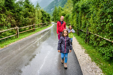 Family hiking on road in nature on a rainy day.