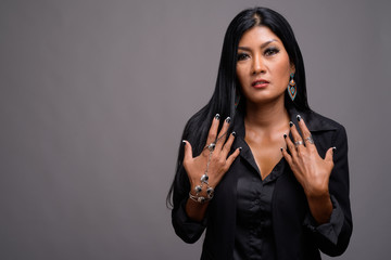 Mature beautiful Asian businesswoman against gray background