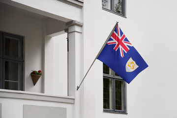 Anguilla flag hanging on a pole in front of the house. National flag waving on a home displaying on a pole on a front door of a building and raised at a full staff.