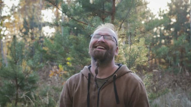 The average pocket plan of a charismatic adult man in a good mood. The object in rectangular glasses with a black frame and a beard pigtail Garibaldi smiles looking at the camera