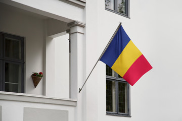 Chad flag hanging on a pole in front of the house. National flag waving on a home displaying on a pole on a front door of a building and raised at a full staff.